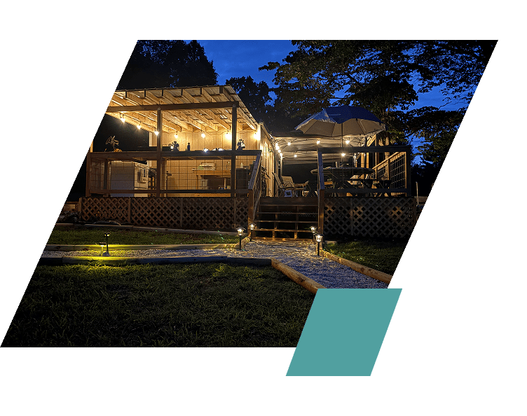 Cozy wooden house warmly lit at night with a garden path.